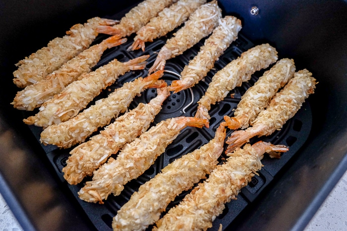 frozen coconut shrimp in rows in black air fryer tray