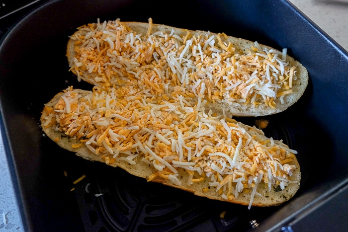 frozen garlic bread with unmelted cheese in black air fryer tray