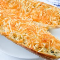 garlic bread with melted cheese on top on white plate
