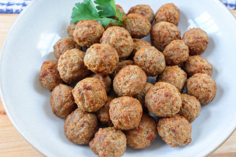 cooked meatballs in bowl with parsley behind