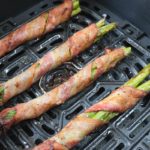 bacon wrapped asparagus in black air fryer tray