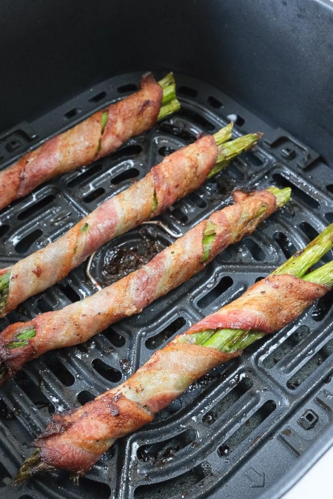 bacon wrapped asparagus in black air fryer tray
