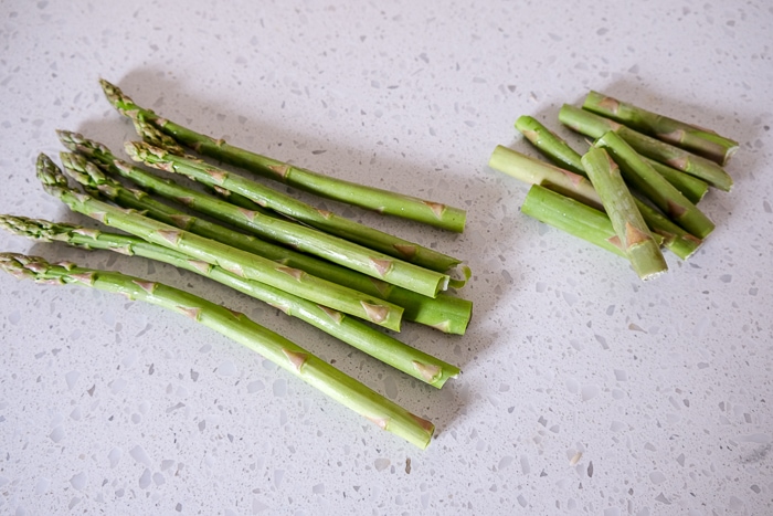 green asparagus with ends cut off on white counter