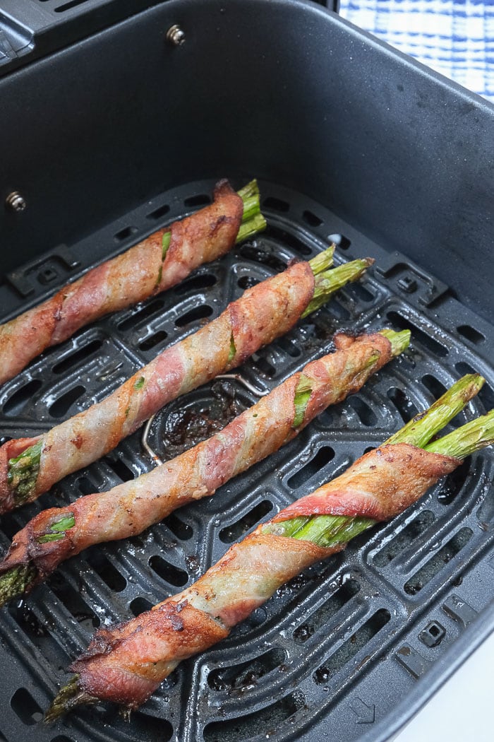 crispy bacon wrapped asparagus in black air fryer tray
