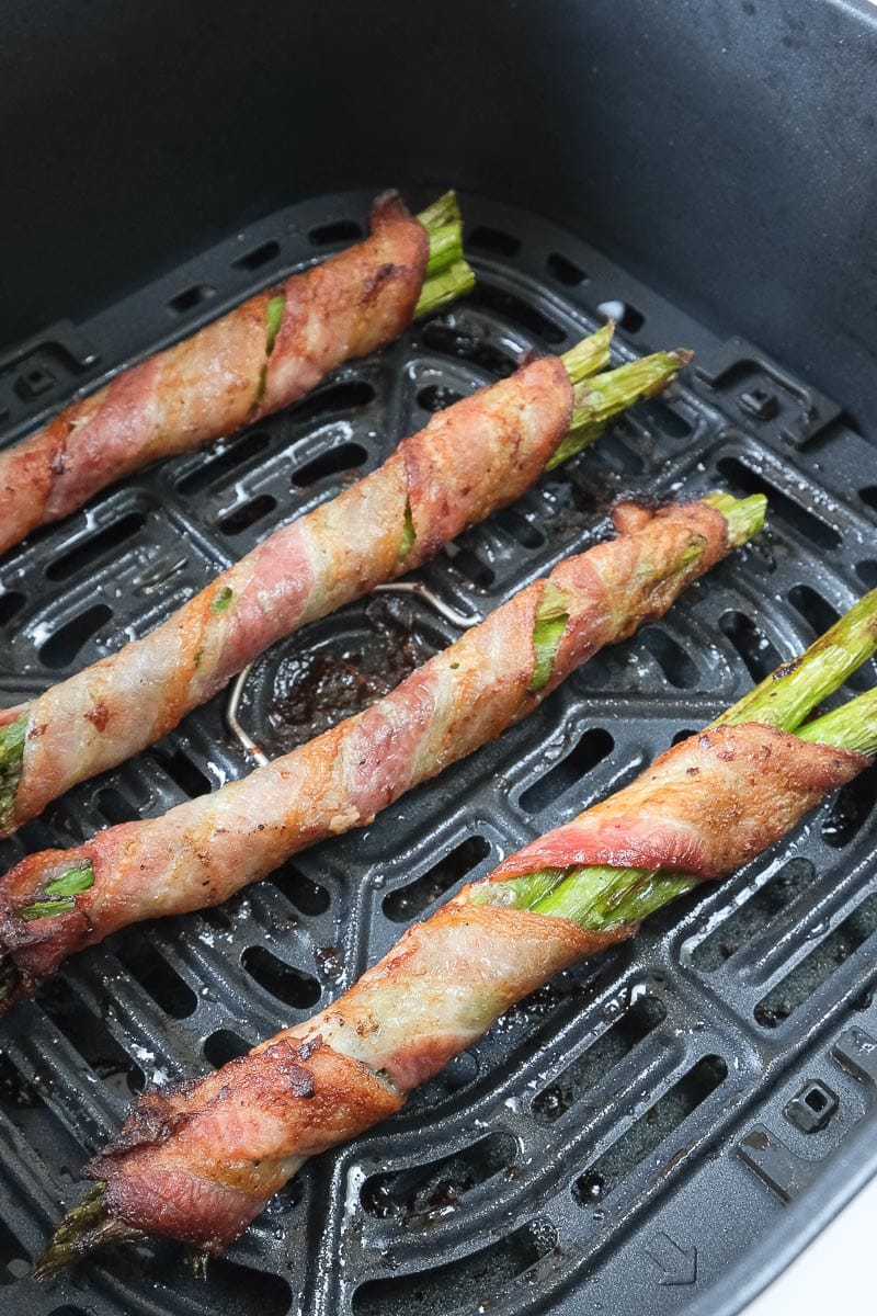 bacon wrapped asparagus in black air fryer tray