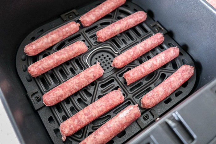 raw breakfast sausages in black air fryer tray on counter