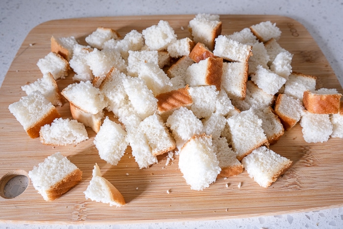 white bread cut into cubes on wooden cutting board