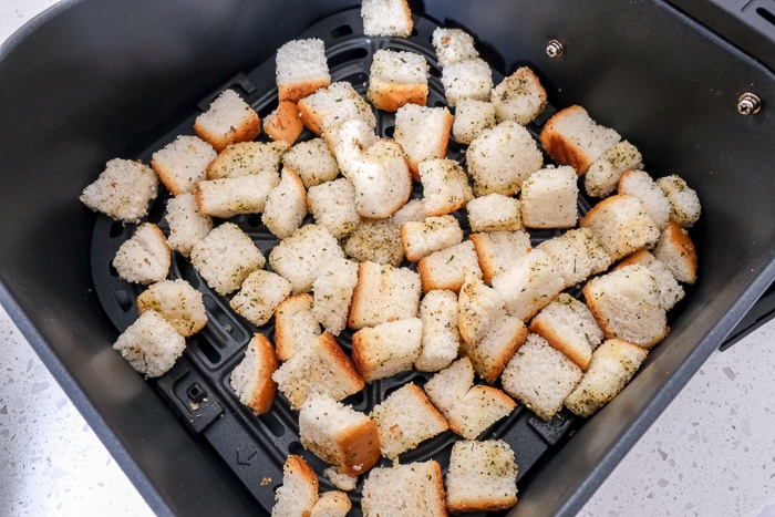 raw croutons in black air fryer tray on white counter