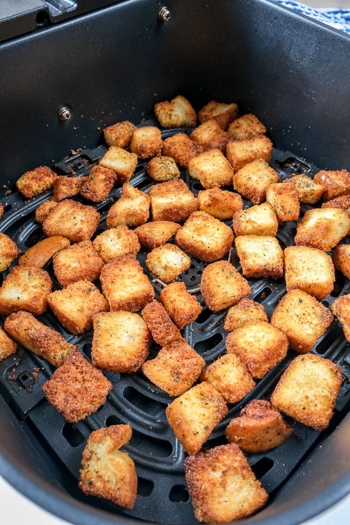 crispy croutons in black air fryer tray on counter