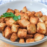 fresh croutons in bowl on wooden board with parsley on top