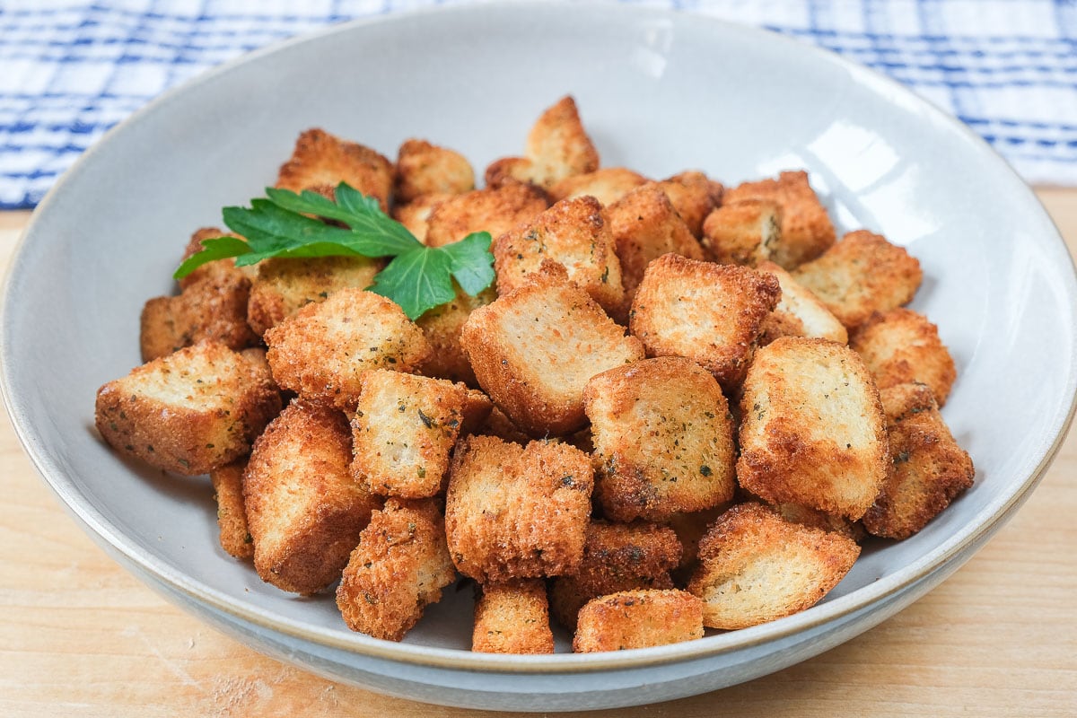fresh croutons in bowl on wooden board with parsley on top