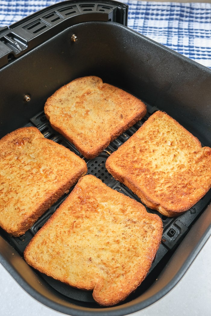cooked pieces of crispy french toast in black air fryer tray