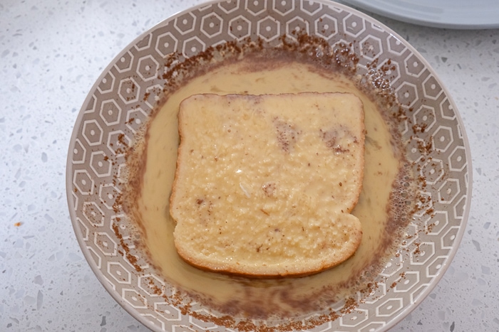 piece of egg soaked bread in bowl on white counter top