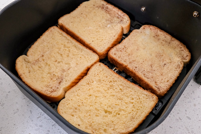 raw french toast slices in black air fryer tray