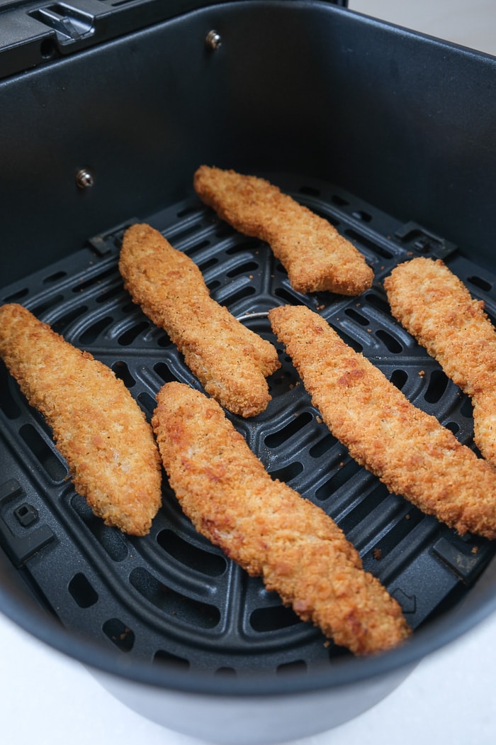 cooked chicken strips in black air fryer basket