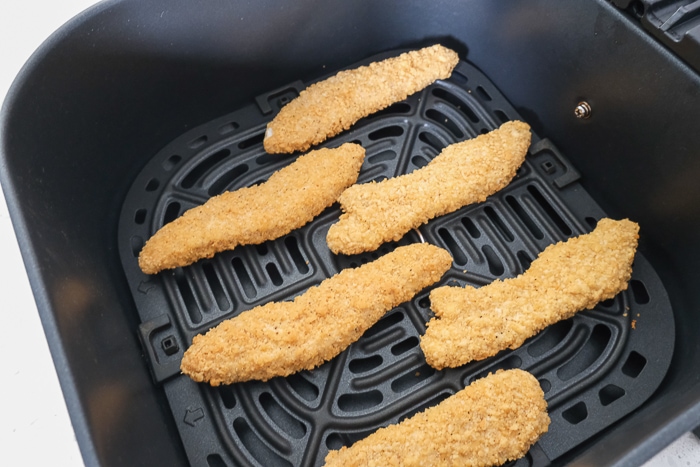 frozen chicken strips in black air fryer tray