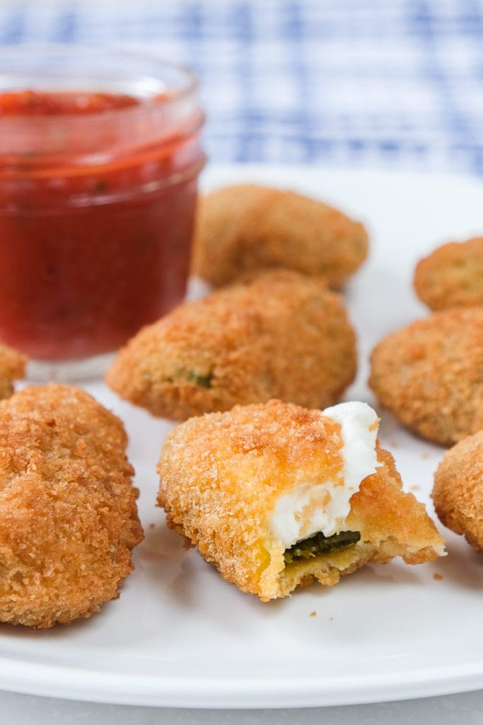 crispy jalapeno poppers on white plate with red sauce behind