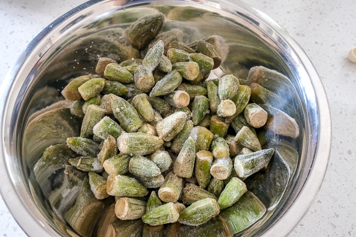 silver mixing bowl filled with frozen okra on white counter