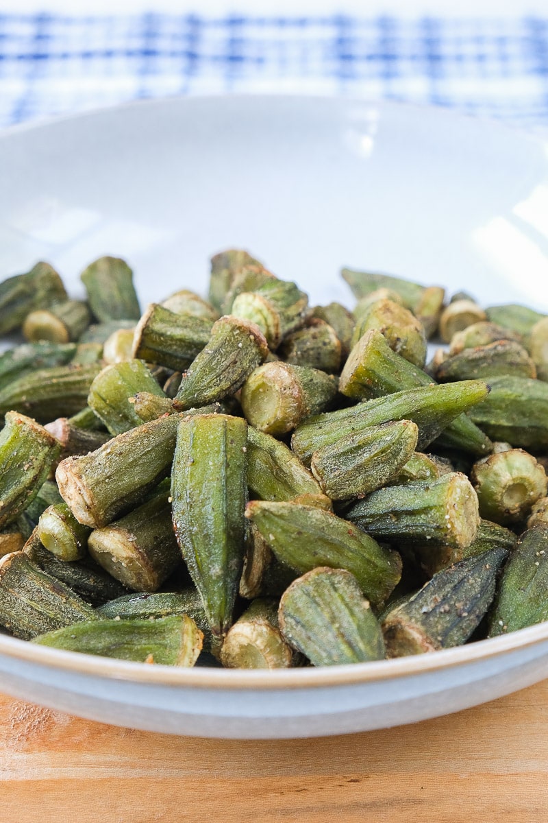 air fried okra in bowl on wooden board with cloth behind