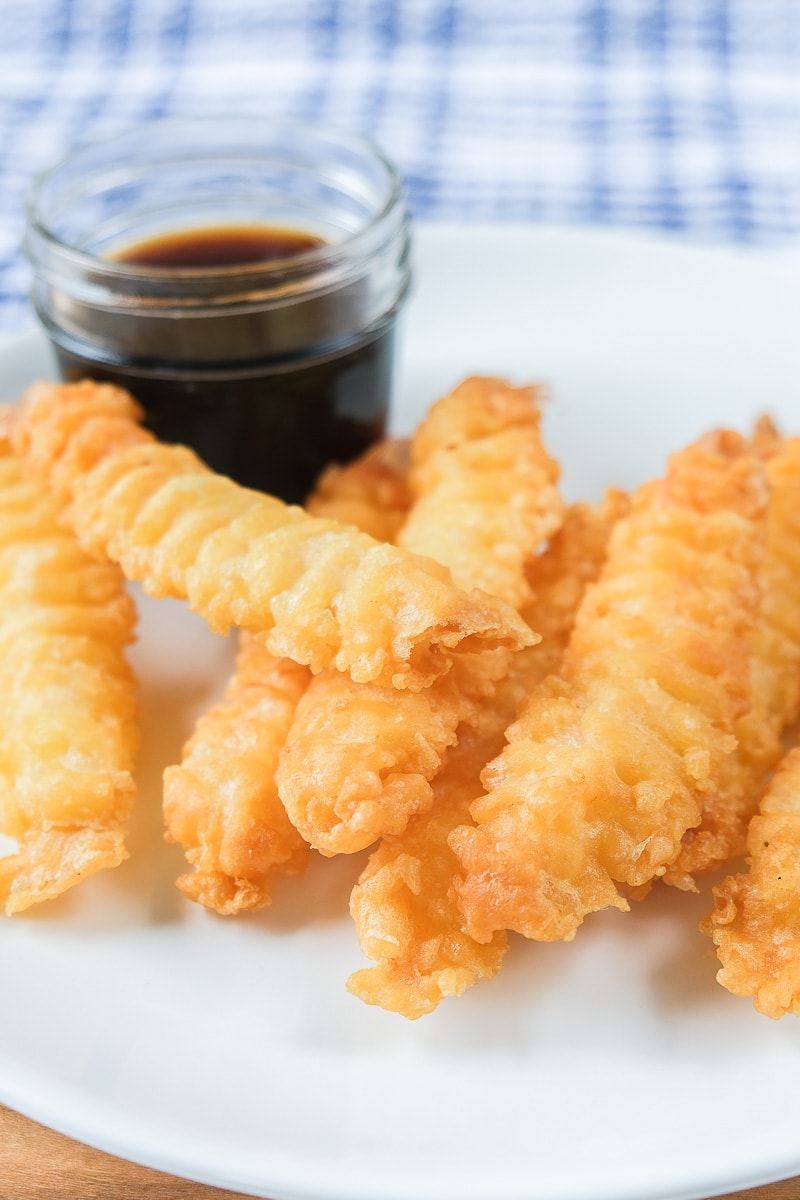 crispy shrimp tempura on white plate with sauce behind