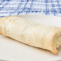 crispy white burrito on plate with blue cloth behind