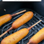 corn dogs in black air fryer basket with text overlay 