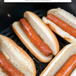 cooked hot dogs in buns in air fryer with text overlay "hot dogs in the air fryer".
