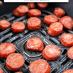 slices of cooked kielbasa in black air fryer with text overlay "kielbasa in the air fryer".
