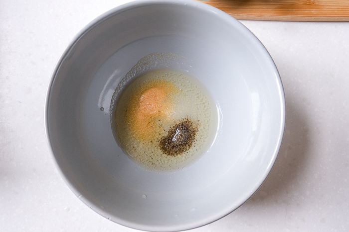 grey bowl of oil and spices in the bottom on white counter