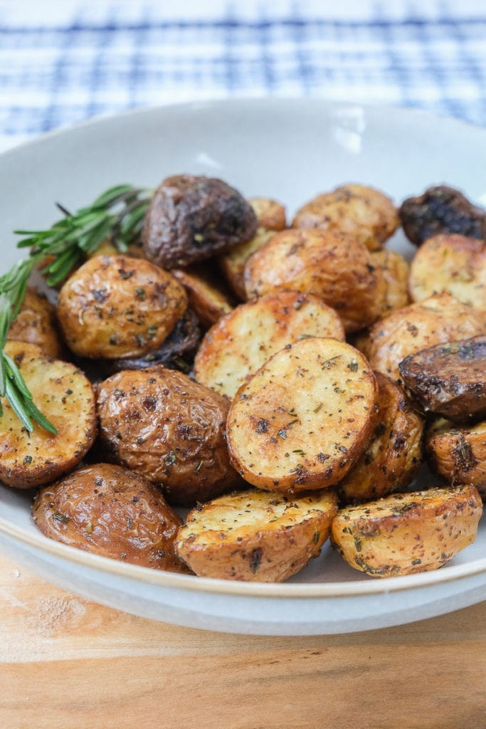 cooked baby potatoes in spices in bowl on wooden board