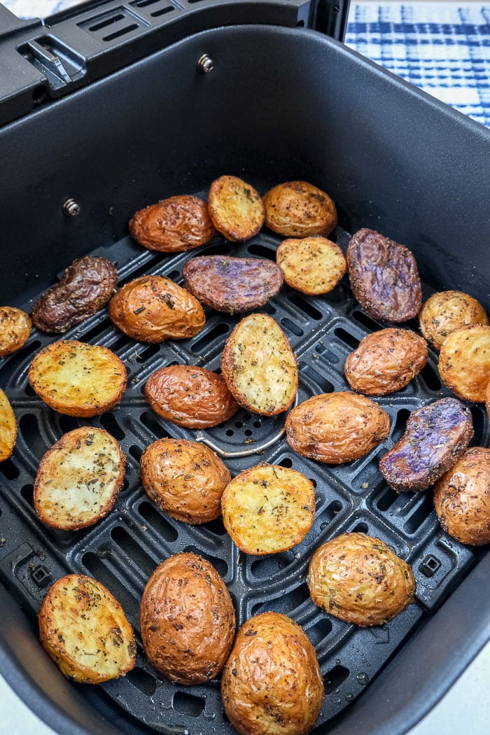 cooked baby potatoes in black air fryer tray on counter
