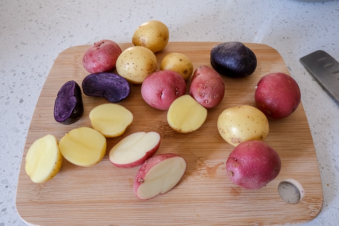 raw baby potatoes on wooden board with knife beside