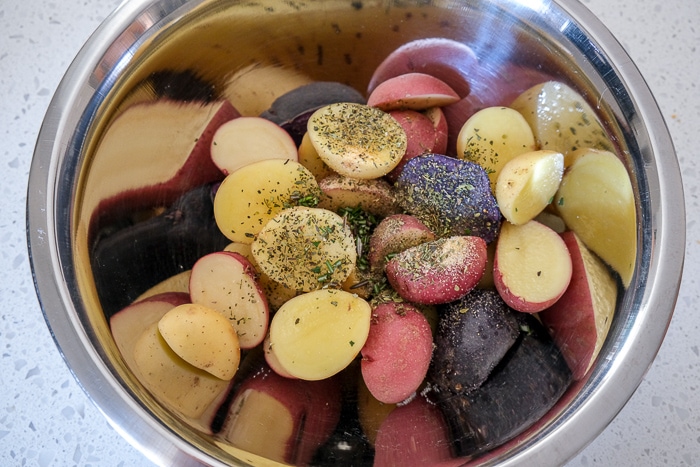 baby potatoes covered in spices in silver bowl on white counter