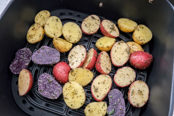 halved colorful baby potatoes in black air fryer tray