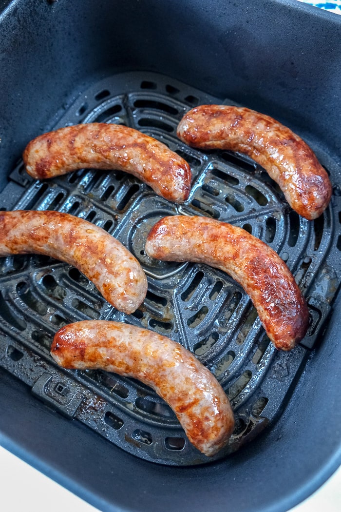 cooked bratwurst sausages in black air fryer tray