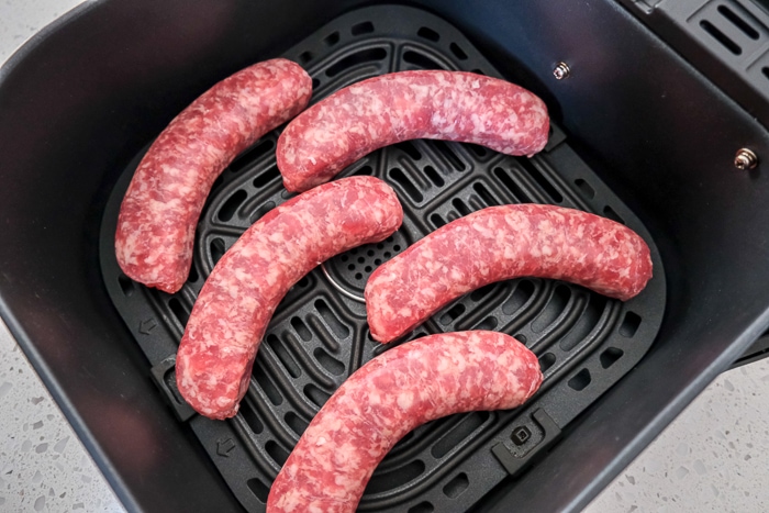 raw bratwurst sausage in black air fryer tray