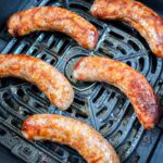cooked brats in air fryer basket.