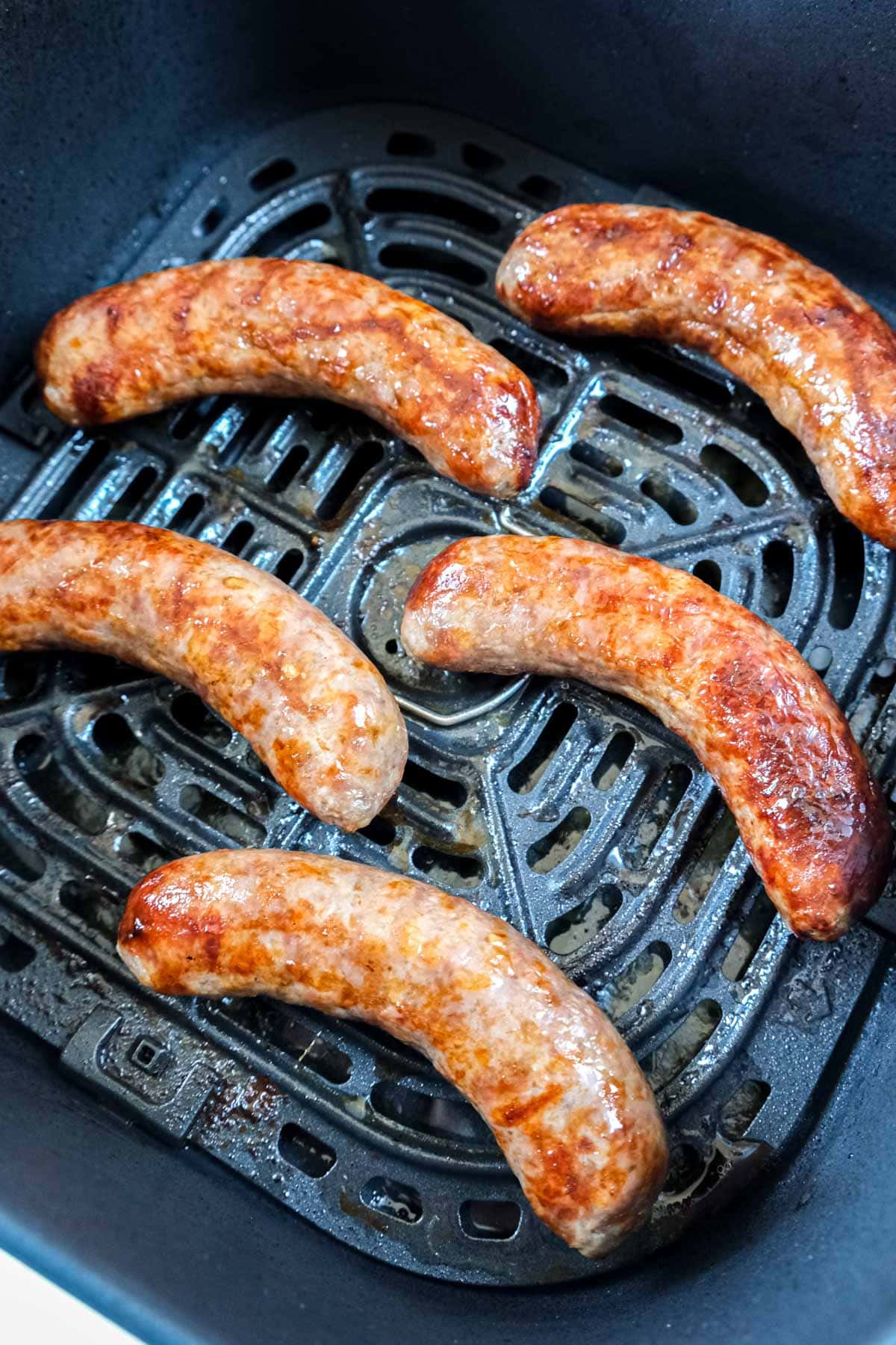 cooked brats in air fryer basket.