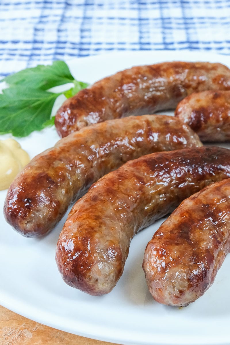 crispy brats on white plate with mustard and parsley beside