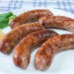 bratwurst sausages on white plate with mustard beside
