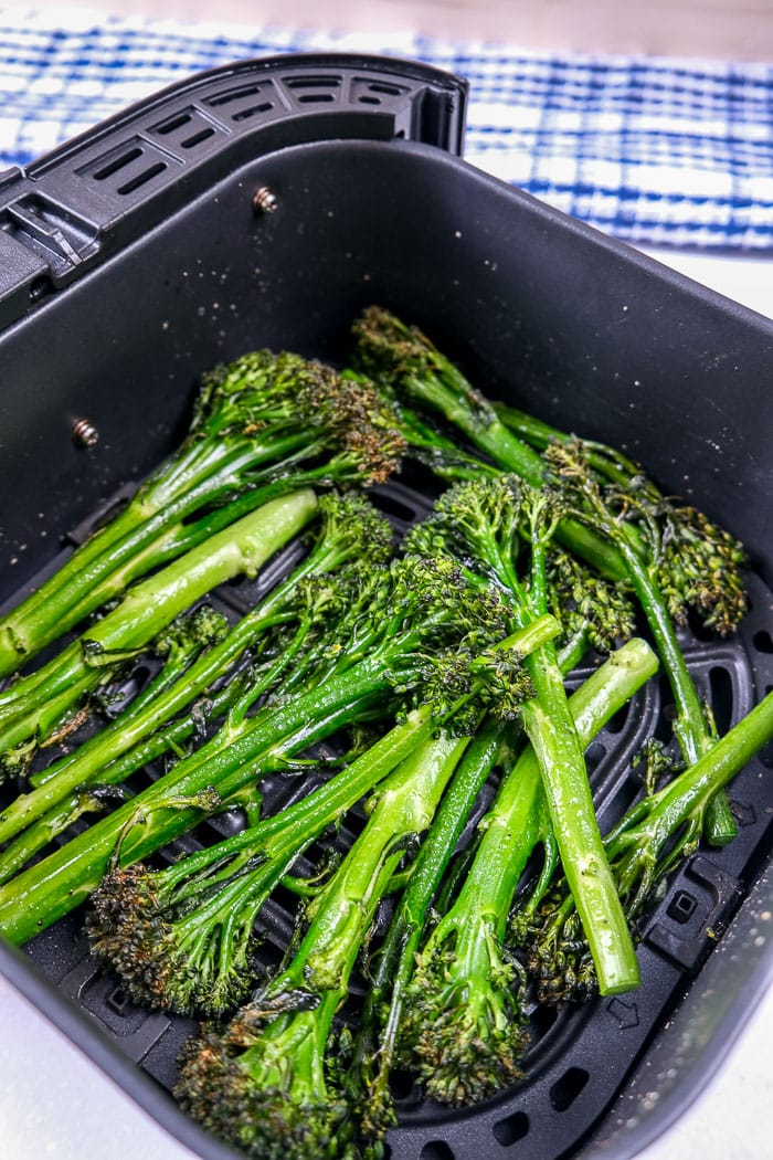 green broccolini in black air fryer tray on counter