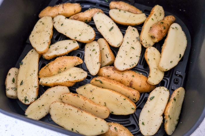 raw fingerling potatoes in black air fryer tray on white counter