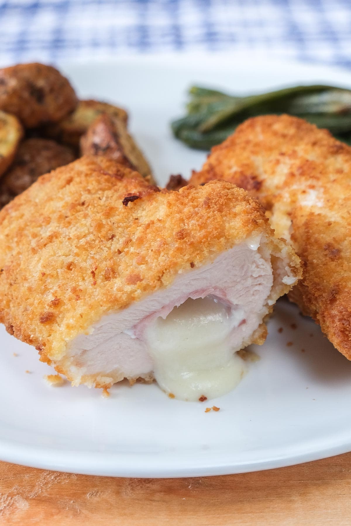 breaded chicken with ham and cheese spilling out on white plate