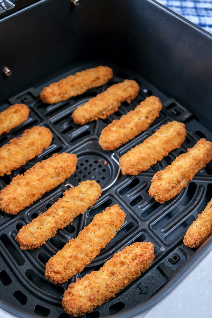 crispy chicken fries in black air fryer tray with cloth behind