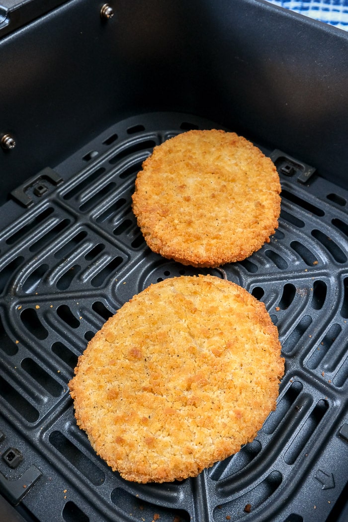 cooked breaded chicken patties in black air fryer tray