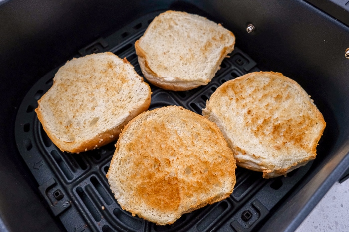 toasted hamburger buns in black air fryer tray