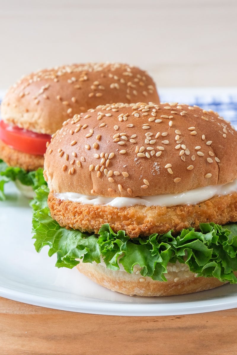 chicken patties in buns with lettuce on white plate