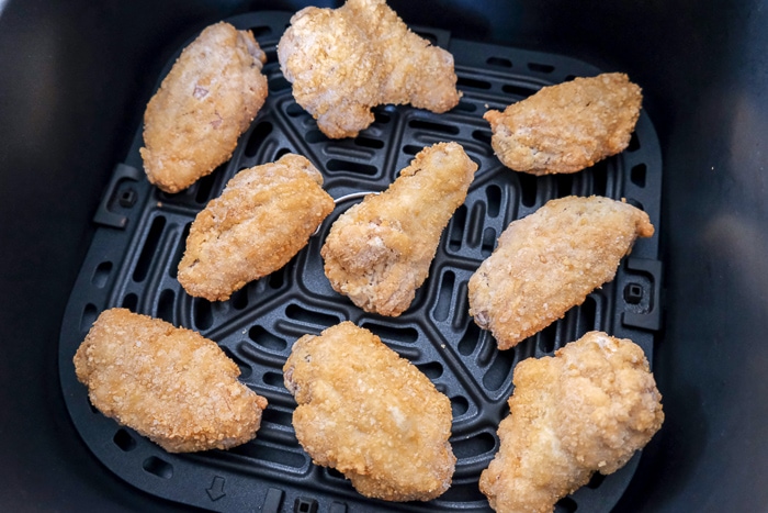 frozen chicken wings in black air fryer tray