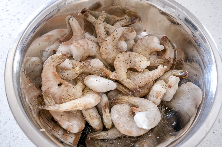 frozen shrimp in silver mixing bowl on white counter