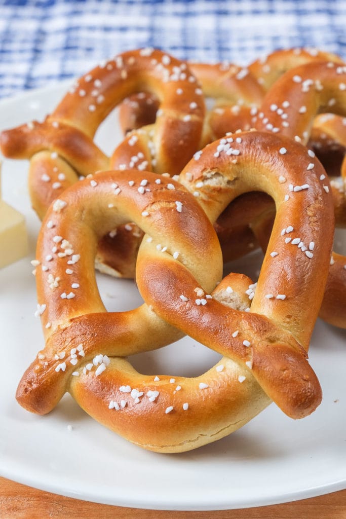 soft pretzels with salt on them on white plate with blue cloth behind
